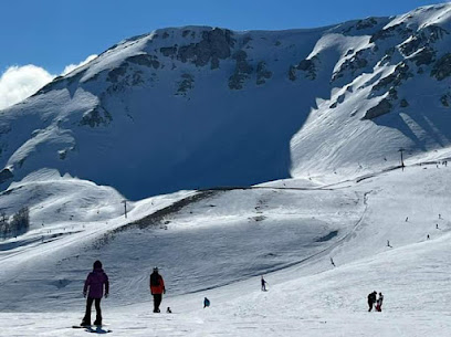 Snow-covered slopes of a ski resort in Piana di Vigezzo Santa Maria Maggiore in Prestinone Italy with a skier enjoying the run and a cozy chalet nearby.