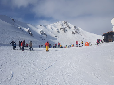 Skiers enjoying winter sports at the Monte Magnola resort in Ovindoli, Italy. A charming chalet completes the snowy landscape.