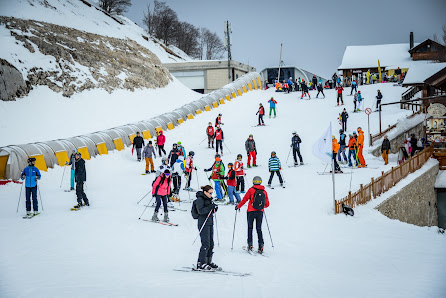 Winter sports scene at Monte Magnola, Ovindoli, featuring a bustling ski resort with several people enjoying various skiing activities amidst a beautiful snow-covered landscape.