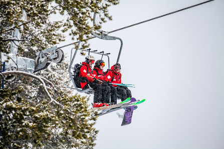 Ski lift ascending up Beaver Mountain amidst a winter sports scene in Garden City, Utah, with people, possibly families and groups, enjoying skiing at the resort.