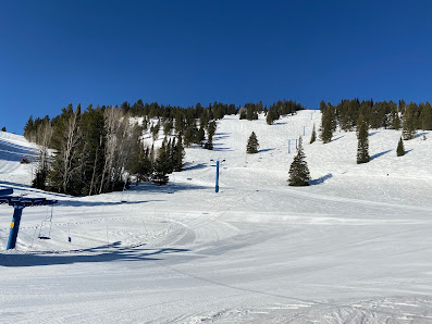 A lively scene at Beaver Mountain ski resort in Utah USA showcasing a winter sports setting with a ski lift and snow-covered slopes. A visible skier enjoys the terrain highlighting the exhilaration of winter activities.
