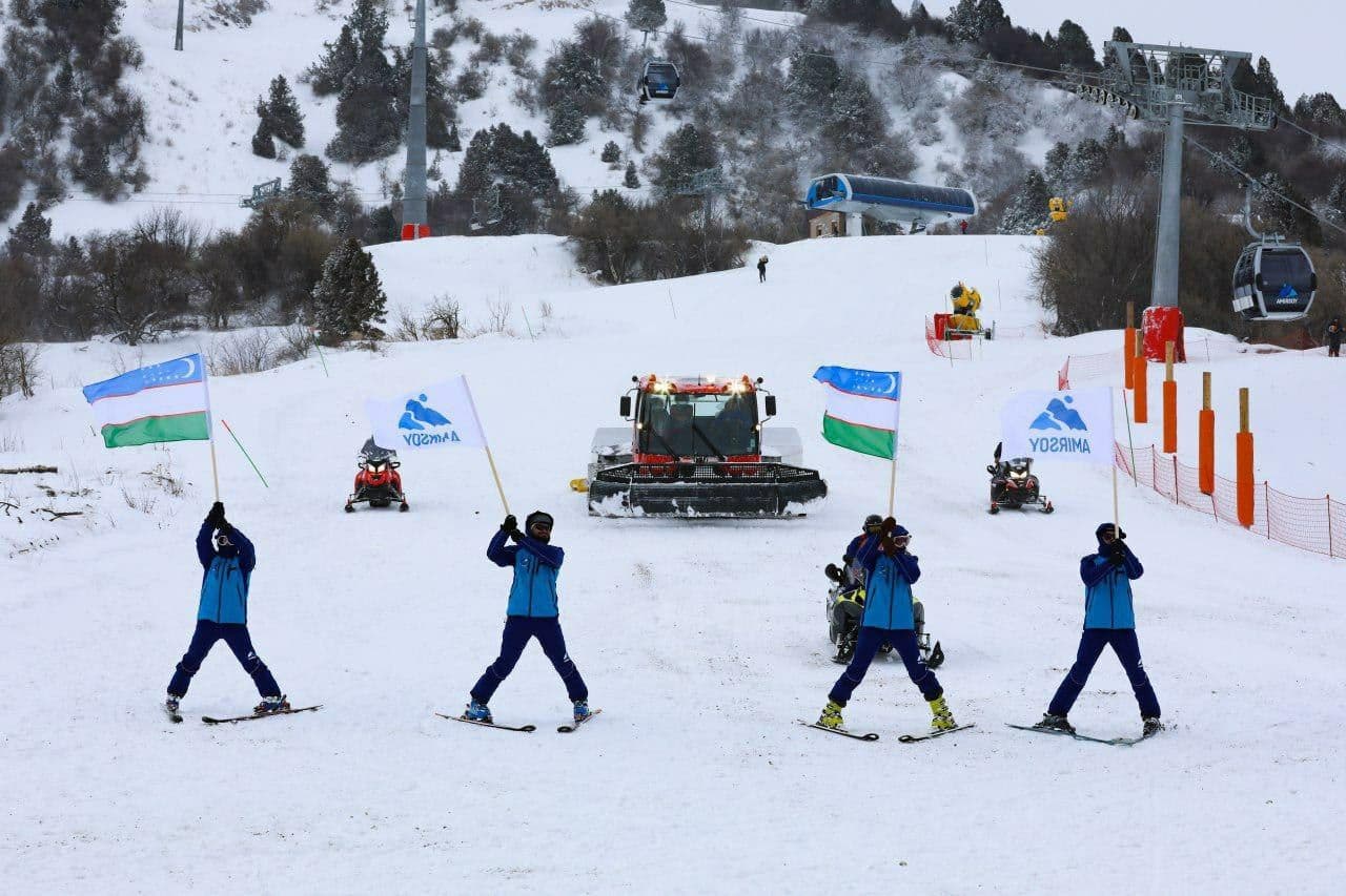 Amirsoy Mountain Resort in Uzbekistan - a group of people riding ski boards down a hill.