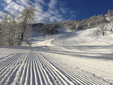 Skier descends a slope at Sangiacomo Cardini – Monte Alpet ski resort in Roburent Italy; charming chalet seen nearby nestled within the snowy winter landscape.