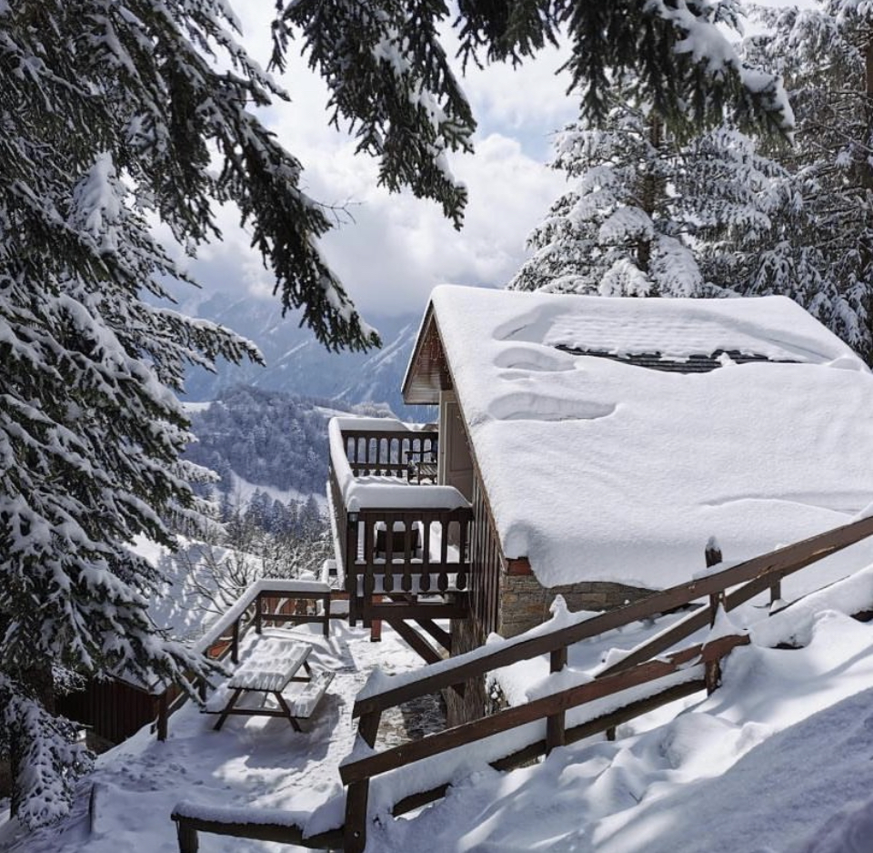 View of the snowy Guzet-Neige winter sports resort in Ariège, France, featuring skiers in action, a quaint chalet, and breathtaking winter scenery.