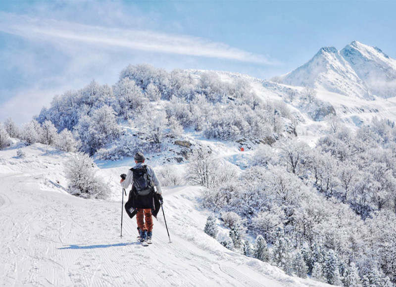 Winter sports enthusiasts enjoying their time at the picturesque Guzet-Neige ski resort in Ariège, France, surrounded by stunning snowy landscape and a cozy chalet.