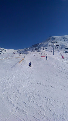 Image of a cozy chalet nestled in Guzet-Neige ski resort, Ariège, France. Skiers enjoy the winter sports scene amidst the pristine snow-covered landscape.