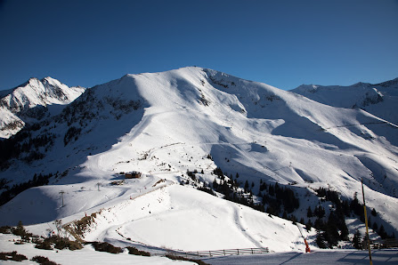 View of a charming chalet in Guzet-Neige, Ariège, France, amidst a thriving ski resort. The landscape is adorned with snow-covered slopes, portraying a lively winter sports scene.