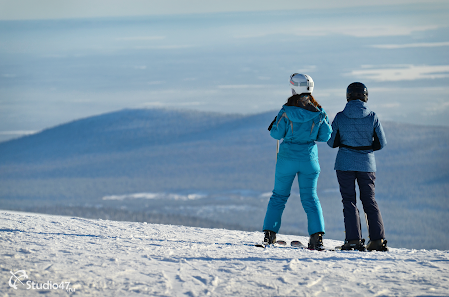 A winter sports scene at Big Wood, Murmansk, Russia with a skier and a group of people, possibly a family, enjoying their time skiing at the resort.