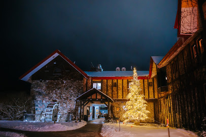 View of The Highlands at Harbor Springs in Michigan, featuring a bustling winter sports centre and lodge. The landscape is dotted with skiers enjoying the well-groomed slopes amidst idyllic winter scenery.