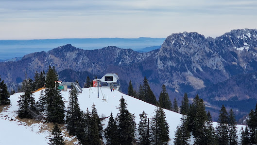 A picturesque Austrian winter scene at Kasberg ski resort in Salzkammergut featuring skiers a ski lift in operation with a charming mountain hut nestled against the impressive snow-covered mountain backdrop.
