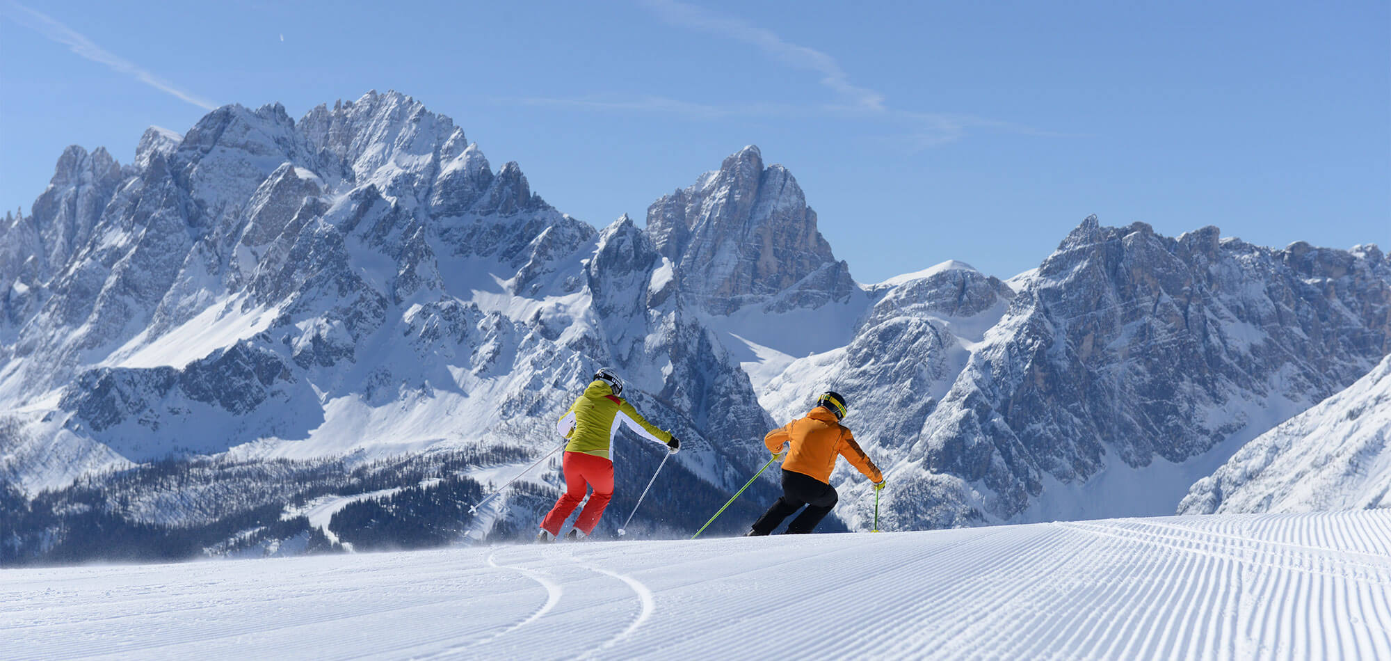 Padola Val Comelico in Italy - two people skiing down a snow covered mountain.