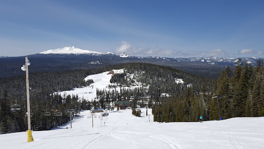 View of Willamette Pass Resort in Oregon, featuring a ski lift soaring over pristine, snow-covered slopes, with a skier enjoying winter sports.