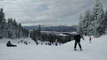A winter scene at Willamette Pass Resort in Oregon USA displaying a skier on a snowy slope with a ski lift and chalet in the background.