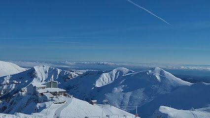 A picturesque view at Snow Summit ski resort in Big Bear Lake California featuring a charming chalet and a skier against the backdrop of a towering mountain in winter season.