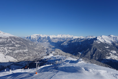A picturesque chalet stands at the center of a ski resort in the snow-clad Mont-Noble in Switzerland. Skiers and winter sports enthusiasts dot the idyllic white landscape.