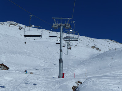 View of the bustling Mont-Noble ski resort in Val d’Hérens Switzerland featuring a charming chalet a busy ski lift carrying skiers up the mountain and exhilarating winter sports activity.