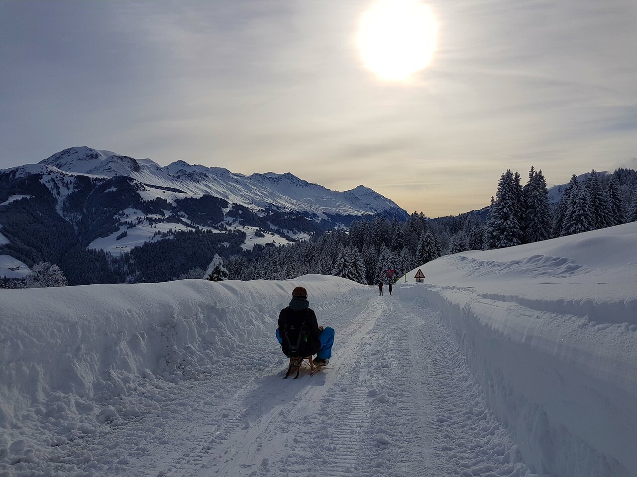Brambrüesch - Chur Bergbahnen in Switzerland - a person walking down a snow covered road.