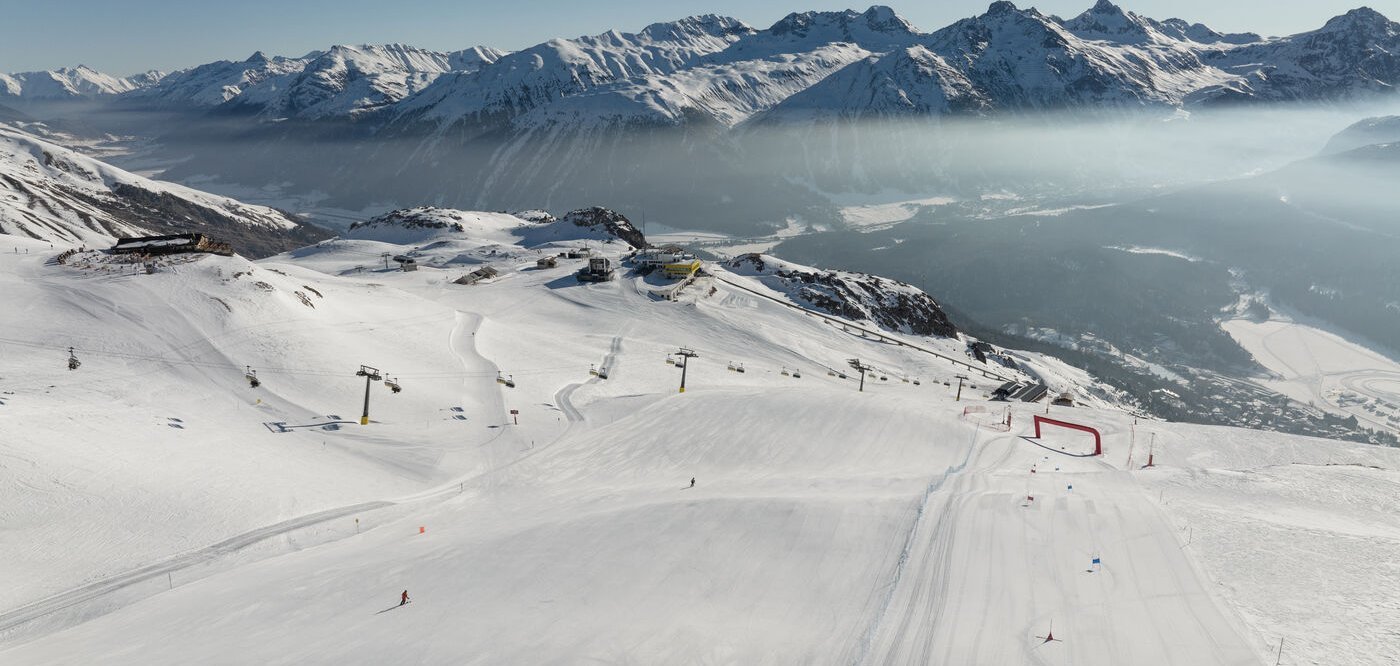 St. Moritz Corviglia in Switzerland - a group of people skiing down a snow covered mountain.