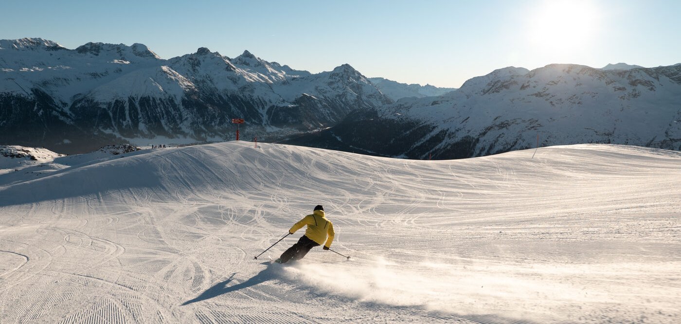 St. Moritz Corviglia in Switzerland - a person skiing down a snowy slope in the mountains.