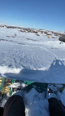 A snowmobile and skier in action against the backdrop of stunning winter scenery including a majestic mountain in Tänndalen Northern Sweden.