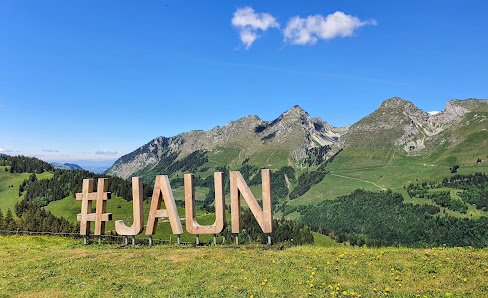 View of the stunning Jaun-Gastlosen Bergbahnen in Switzerland on a sunny day, featuring a prominent mountain and charming chalet.