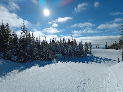 Winter scene at Valinouet ski resort in Quebec, Canada, featuring skiers and a snowmobile, with a ski lift set against the beautiful snowy landscape.