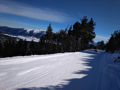 Winter sports scene at Formiguères in France featuring a skier gliding downhill past a charming challet amidst scenic ski resort and stunning winter scenery.