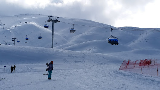 Ski lift at a resort in Nikfer, Tavas/Denizli, Turkey, with a chalet in the background. Skiers are enjoying winter sports in the snowy scene.