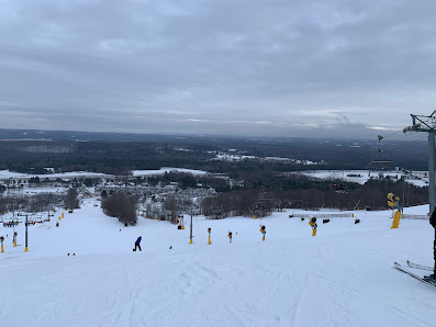 Winter scene at Mount St. Louis Moonstone ski resort in Southern Ontario, showing a skier descending a snowy hill, a chalet in the background, and a ski lift nearby.