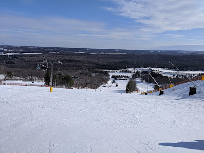A vibrant winter scene at Mount St. Louis Moonstone ski resort in Southern Ontario showcasing a skier in action a ski lift nearby and a charming chalet nestled against the snow-clad backdrop.