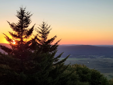 A sunny day at Timberline Mountain in Davis West Virginia showcasing a charming chalet nestled against the scenic backdrop of a vast mountain range fringed by a lush forest.