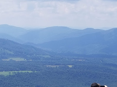 An expansive view of Timberline Mountain in Davis, West Virginia, under a brilliant blue sky. The mountain's rugged terrain is bathed in sunlight, creating soft shadows and enhancing its majestic beauty.