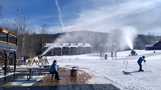 Winter scene at Timberline Mountain, West Virginia showcasing a bustling ski resort with numerous skiers, visible ski lifts, and a well-prepared sporting centre amidst the snowy landscape.
