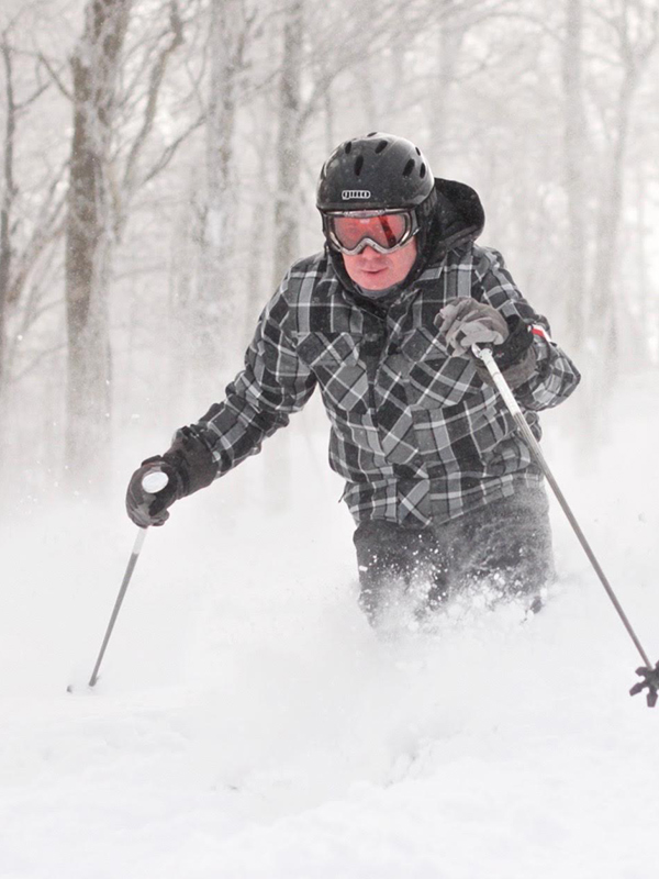 A skier gracefully gliding down the snowy slopes of Timberline Mountain in Davis West Virginia with other winter sports enthusiasts enjoying the pristine surroundings.
