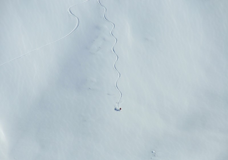A skier enjoying a winter day on the slopes of Bonneval sur Arc in Savoie Mont Blanc, France. Nearby, a charming chalet and a ski lift enhance the idyllic winter sports scene.