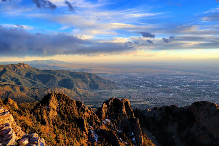 View of Sandia Peak in New Mexico, showcasing a panoramic mountain scene under a clear, sunny sky. A chalet can be seen in the background and a mountain bike hints at outdoor activities.