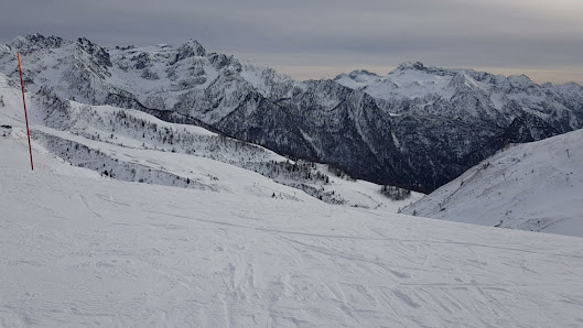Image of a skier on the snow-covered slopes at Foppolo - Carona - Brembo Ski resort in Lombardy, Italy. A cozy chalet sits nearby, completing the winter sports scene.