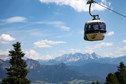 View of a ski lift trailing up the snow-covered slopes of Rittner Horn in South Tyrol, Italy. A small, somewhat distant chalet can be seen against the backdrop of the magnificent mountain range.
