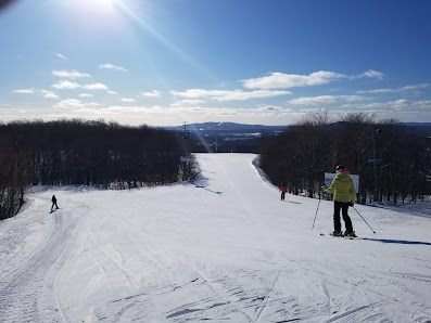 Winter landscape at Le Relais ski resort in Capitale-Nationale, Lac-Beauport, Quebec, with a skier in motion, families enjoying a ski day and a ski lift in the background.