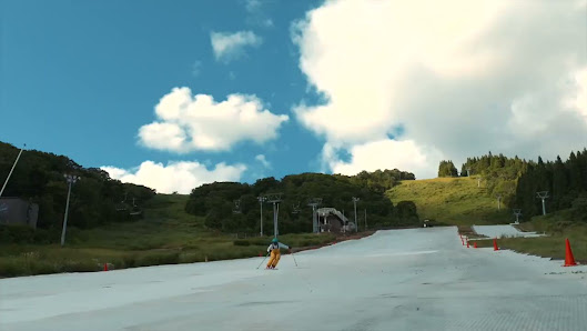 Skiers enjoying a sunny day on the slopes at Winghills Shirotori Resort in Japan. The stunning mountain backdrop frames a ski lift carrying more adventurers up for their run.