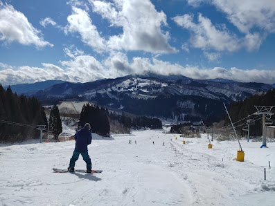 A snowboarder skillfully descends the pristine slopes of Winghills Shirotori Resort in Chūbu, Gifu, honing his craft amidst the stunning natural beauty of Honshu, Japan.