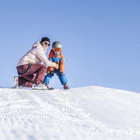 A family enjoying a fun skiing day in Schetteregg - Egg, Bregenz, Austria. The scene captures the thrill of winter sports with an adult leading, followed by a child learning to ski.