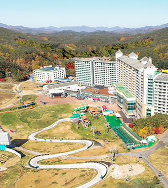 Image showcasing the scenic winter view at Welli Hilli Park, Dunnae-myeon, with a ski resort, a sprawling white landscape, and mountains in the background.