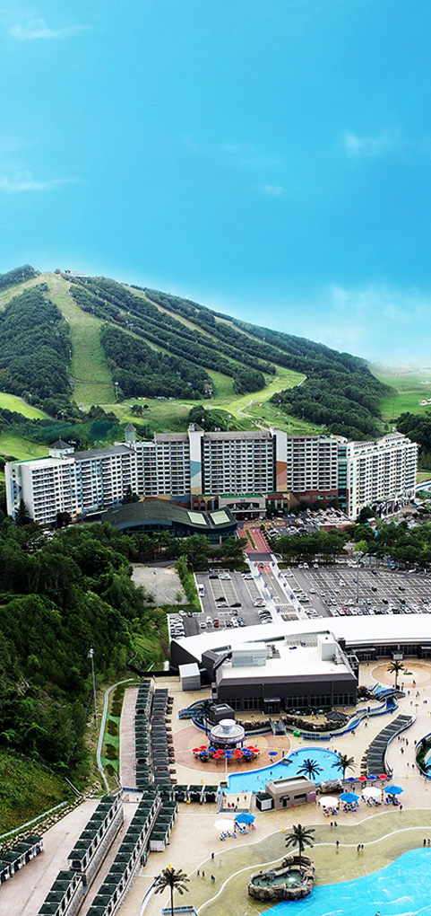 View of Welli Hilli Park, a popular ski resort in South Korea, with a charming chalet nestled amongst snow-covered mountains under a clear, wintry sky.