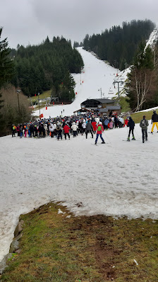 Winter scene at Station de ski alpin - La Mauselaine in Vosges, France featuring a bustling ski resort, a quaint challet, and a ski lift.