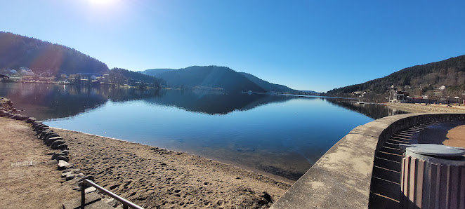 A sunny day at the Station de ski alpin - La Mauselaine in Gérardmer, France. A charming chalet overlooks a placid lake amidst a stunning winter scenery.
