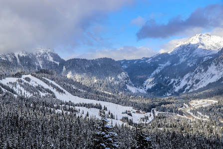 A captivating winter scene at The Summit at Snoqualmie in Snoqualmie Pass Washington featuring a dynamic winter sports scene amid a picturesque ski resort with towering snow-covered mountains in the backdrop.