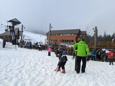 A scene at The Summit at Snoqualmie ski resort in Washington showing winter sports activities with a ski lift and a skier in action.