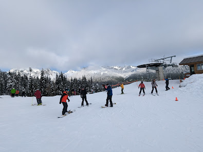 A bustling winter sports scene at The Summit at Snoqualmie in Snoqualmie Pass Washington with skiers enjoying the slopes a ski lift in operation and a ski resort visible in the background.
