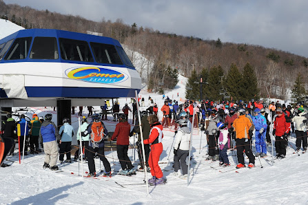 A lively winter sports scene at Bristol Mountain Ski Resort in New York featuring a ski lift with skiers enjoying the pristine snowy slopes.